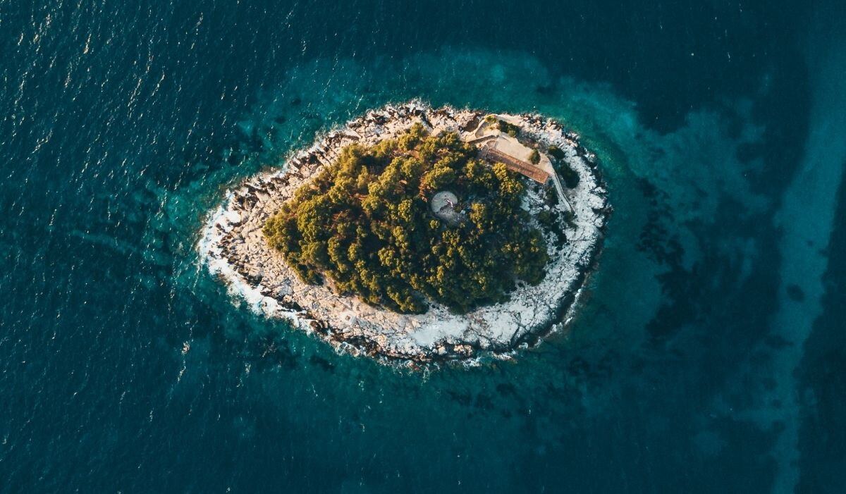 Kleine Insel im türkisen Meer aus der Luft